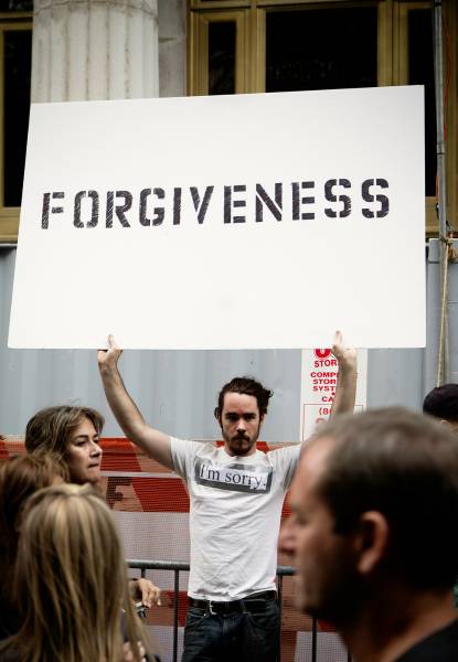 ek ladka forgiveness ka board liye khada hai 